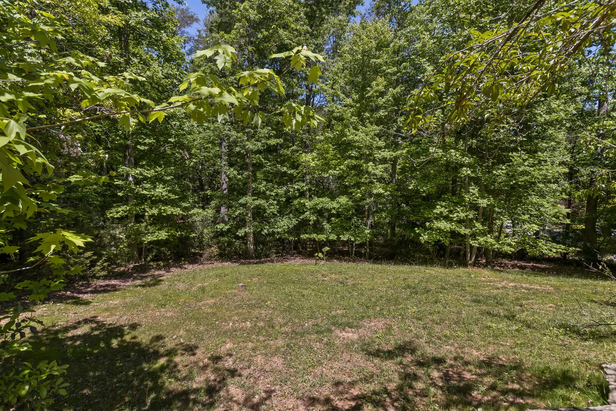 A lush, open grassy area surrounded by mature green trees, ideal for picnicking, relaxing, or exploring. The natural, inviting landscape suggests quiet moments and scenic views, aligning with the tranquil character of the community.