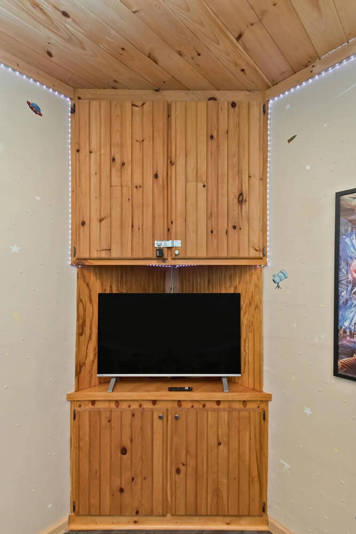 A cozy indoor corner with a television, wooden cabinetry, and tasteful wall decor. The arrangement suggests a comfortable spot for streaming, gaming, or virtual meetings, emphasizing the tech amenities available inside the home.